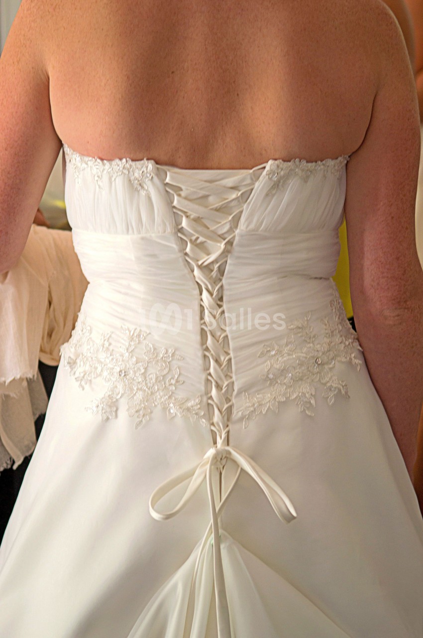 Vue arrière d'une robe de mariée blanche avec un corset lacé et des détails en dentelle.