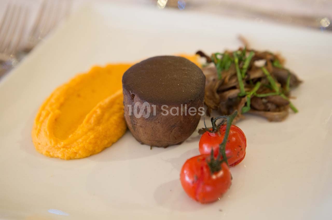 Assiette avec purée orange, pièce de viande, champignons sautés et tomates cerises grillées.