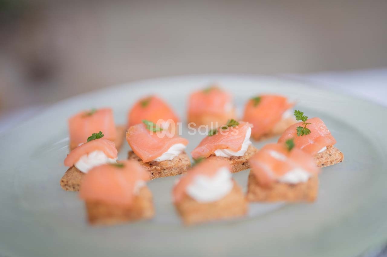 Assortiment de canapés au saumon fumé, crème et herbes fraîches, disposés sur une assiette claire.