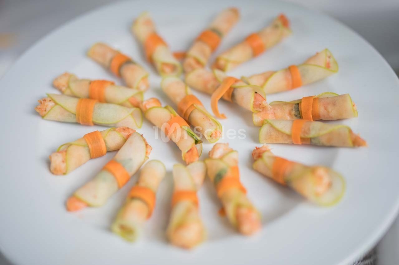Assortiment de rouleaux apéritifs garnis de légumes, présentés en cercle sur une assiette blanche.