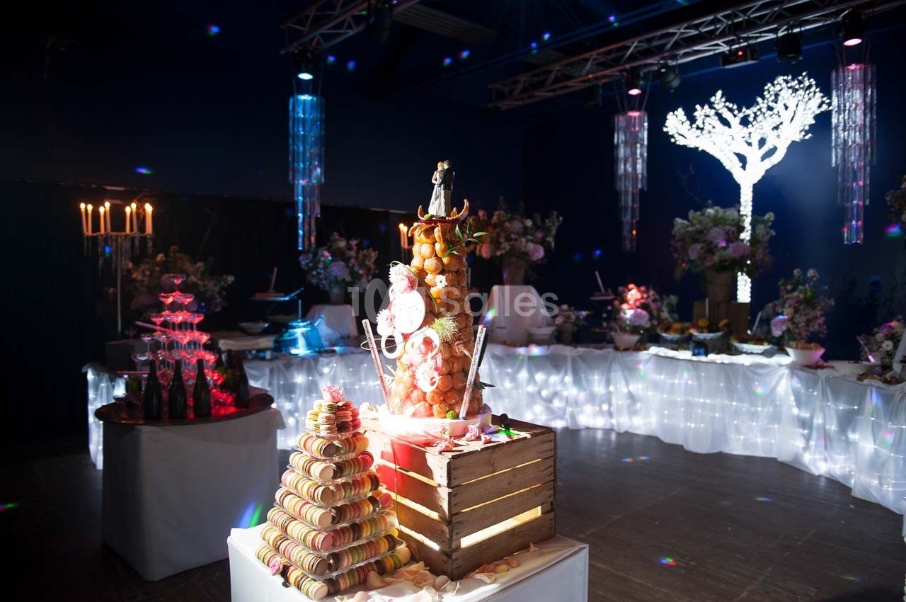 Table décorée pour une réception avec une pièce montée de macarons et des lumières d'ambiance colorées.