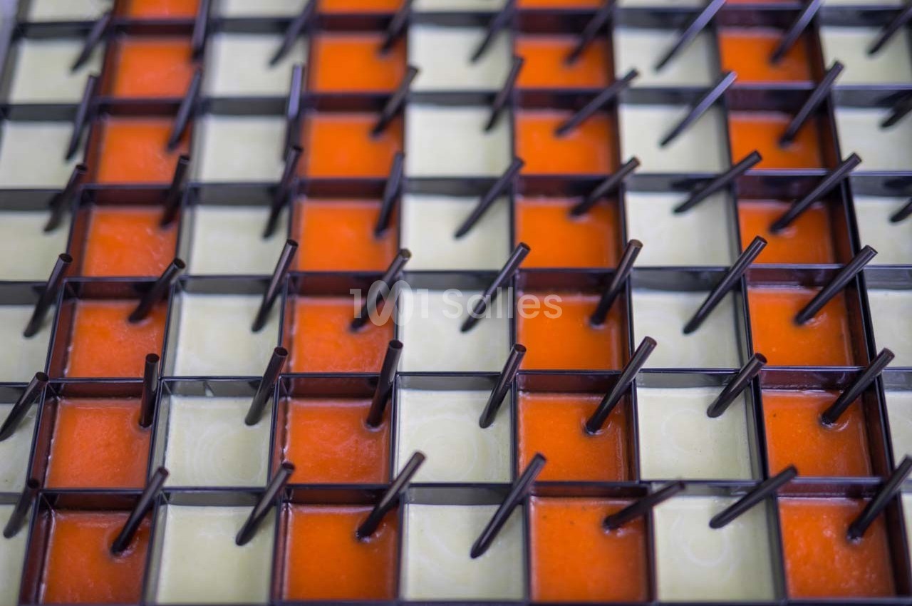 Grille métallique avec des tiges verticales, posée sur un fond alternant carreaux orange et beige.