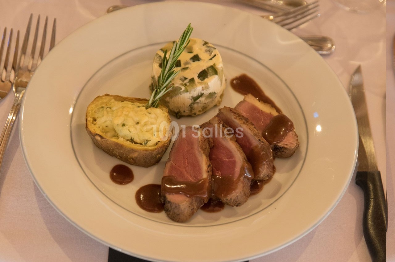 Assiette composée de tranches de viande sauce brune, d'une pomme de terre farcie et d'un flan aux herbes.