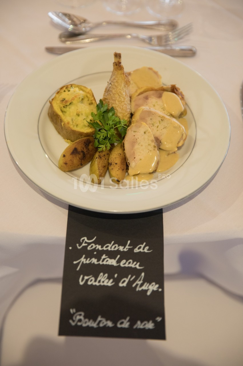 Assiette de pintade avec sauce, pommes de terre, flan de légumes et garniture de persil, servie sur une table dressée.