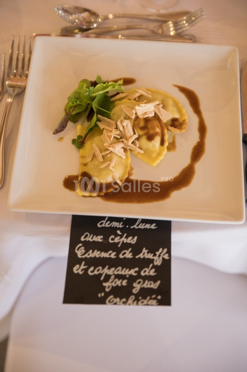 Assiette de ravioles garnies de cèpes, nappées de sauce, décorées de copeaux de foie gras et accompagnées de salade verte.