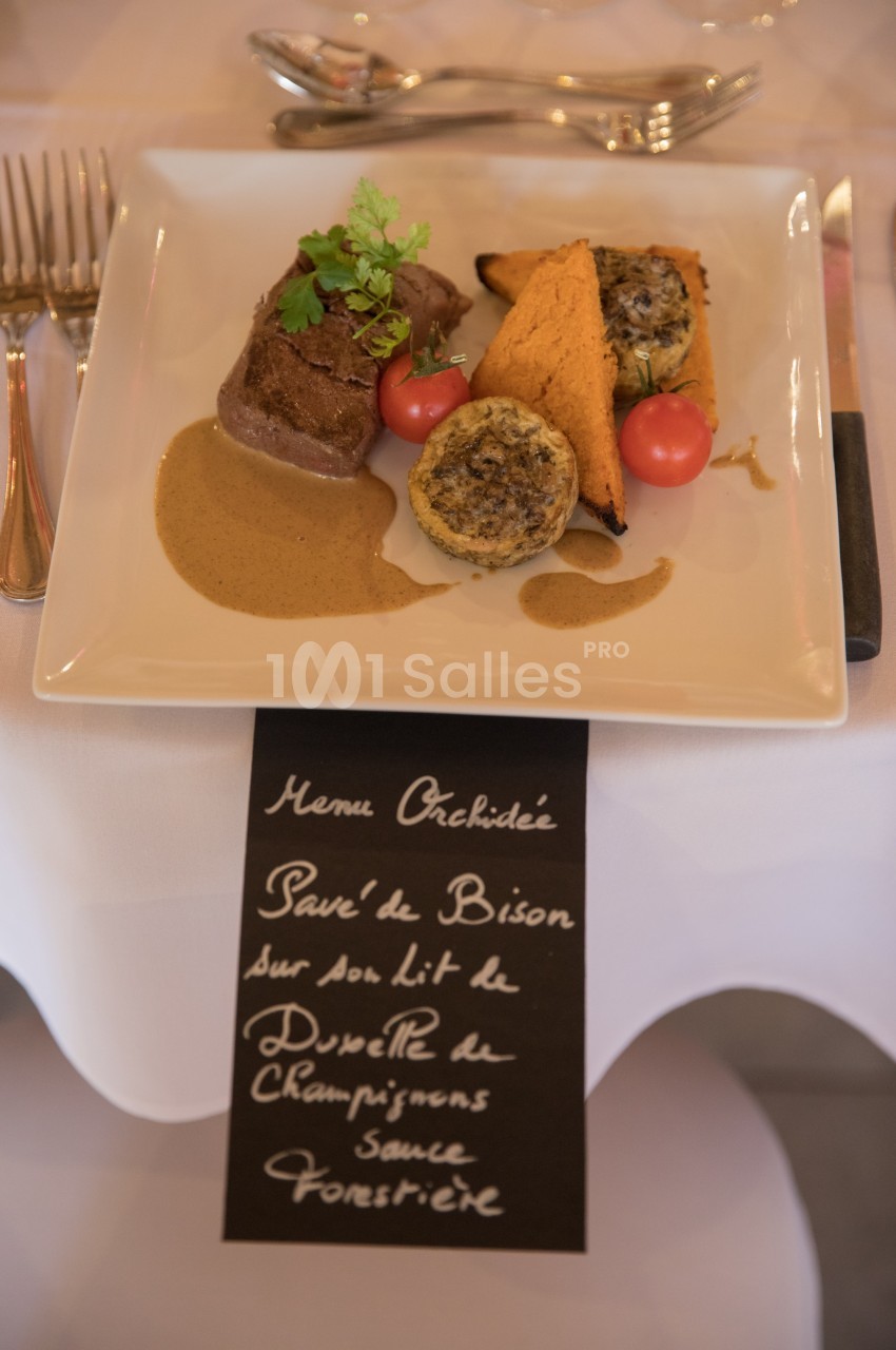 Assiette de pavé de bison avec sauce forestière, accompagnée de légumes et d'une écriture manuscrite en dessous.