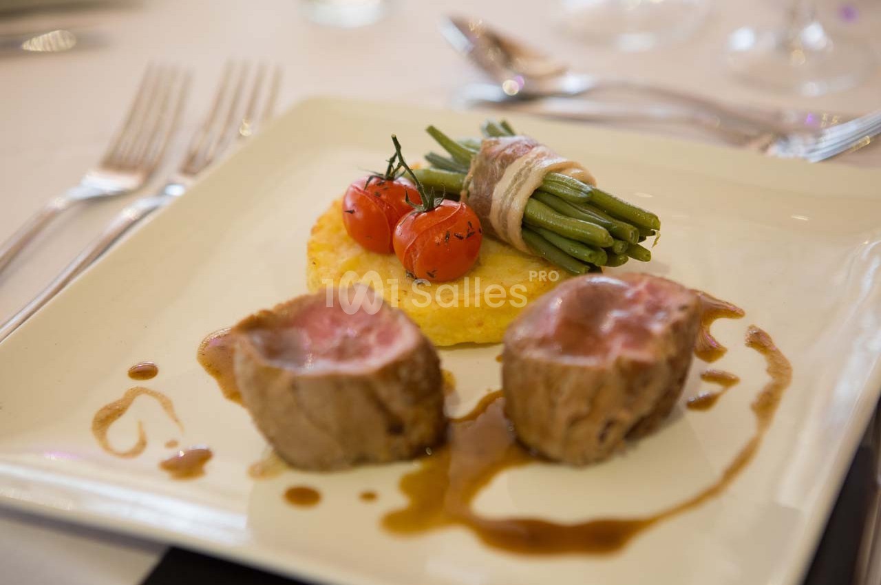 Assiette de viande rosée avec haricots verts enroulés de lard, tomates cerises et galette de pommes de terre.