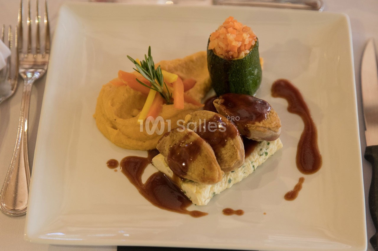 Assiette gastronomique avec viande nappée de sauce, purée de légumes, courgette farcie et garniture colorée.