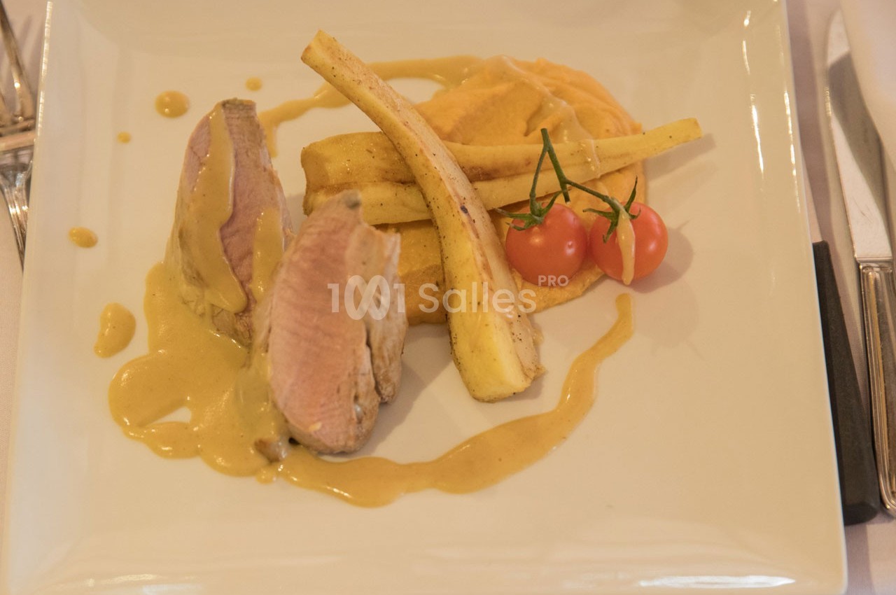 Assiette avec filet de viande nappé de sauce, purée, légumes racines rôtis et tomates cerises.