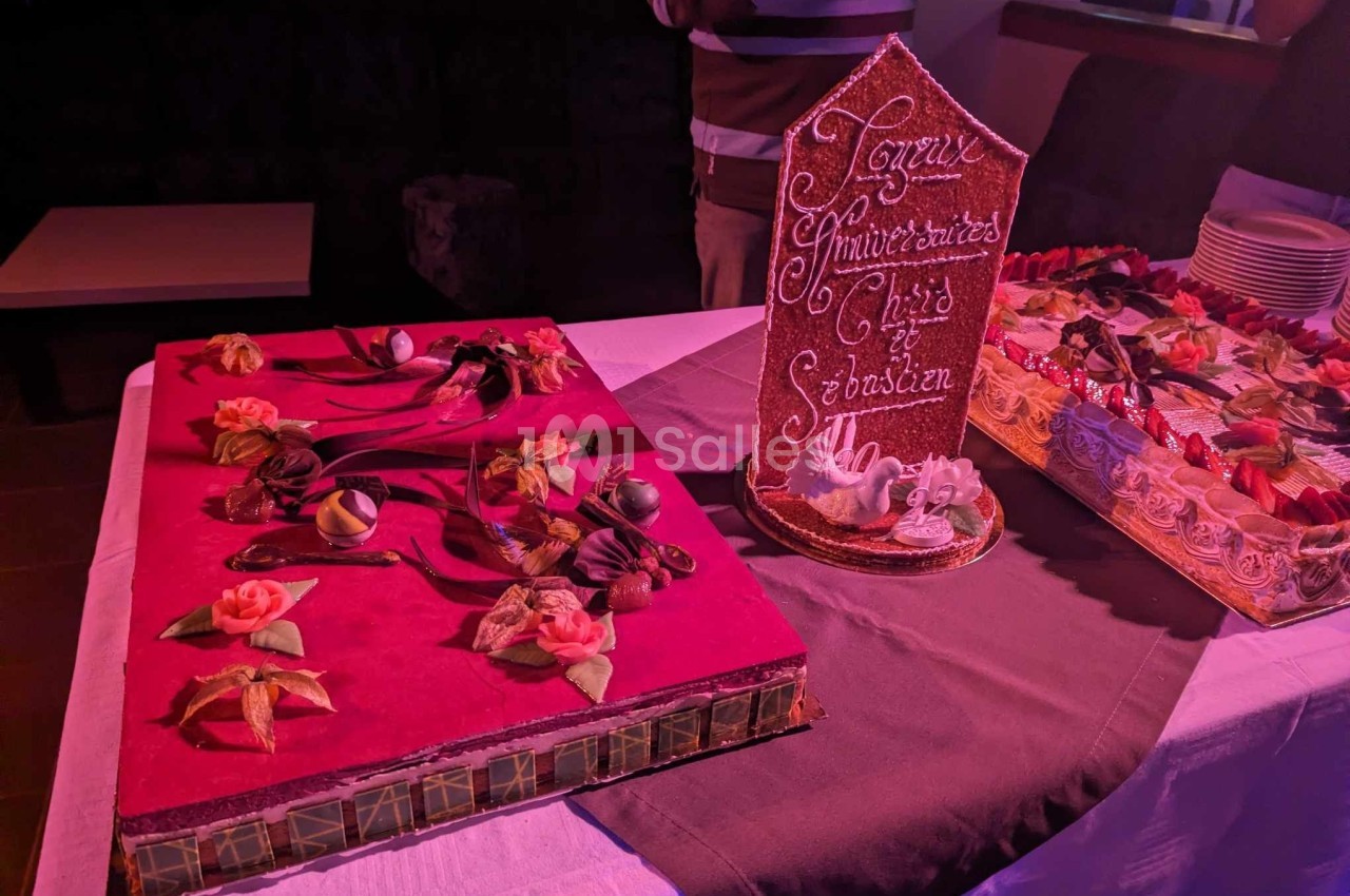 Gâteau en forme de livre décoré de fleurs en sucre, accompagné d'une pièce montée avec un message d'anniversaire.