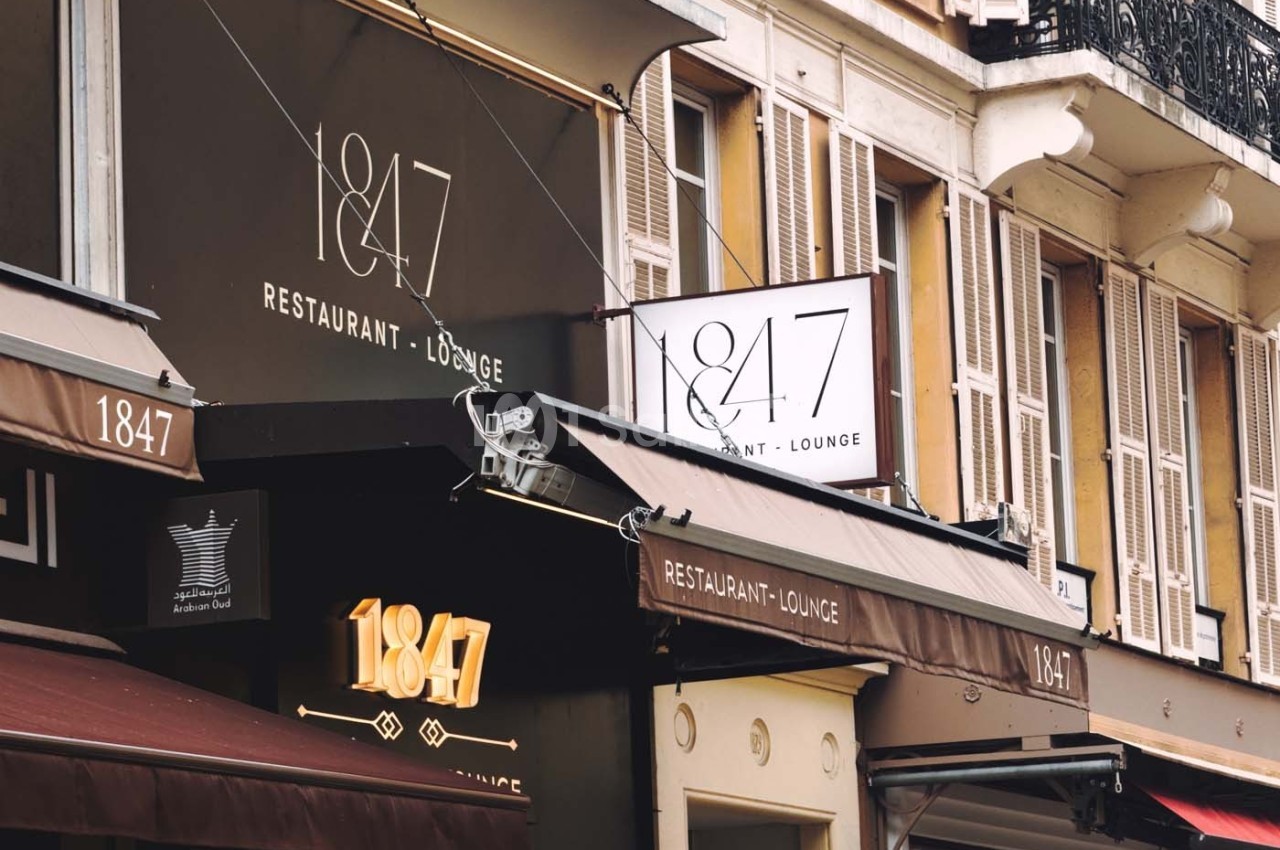 Façade d'un restaurant-lounge nommé ’1847’ avec enseignes visibles et immeubles en arrière-plan.