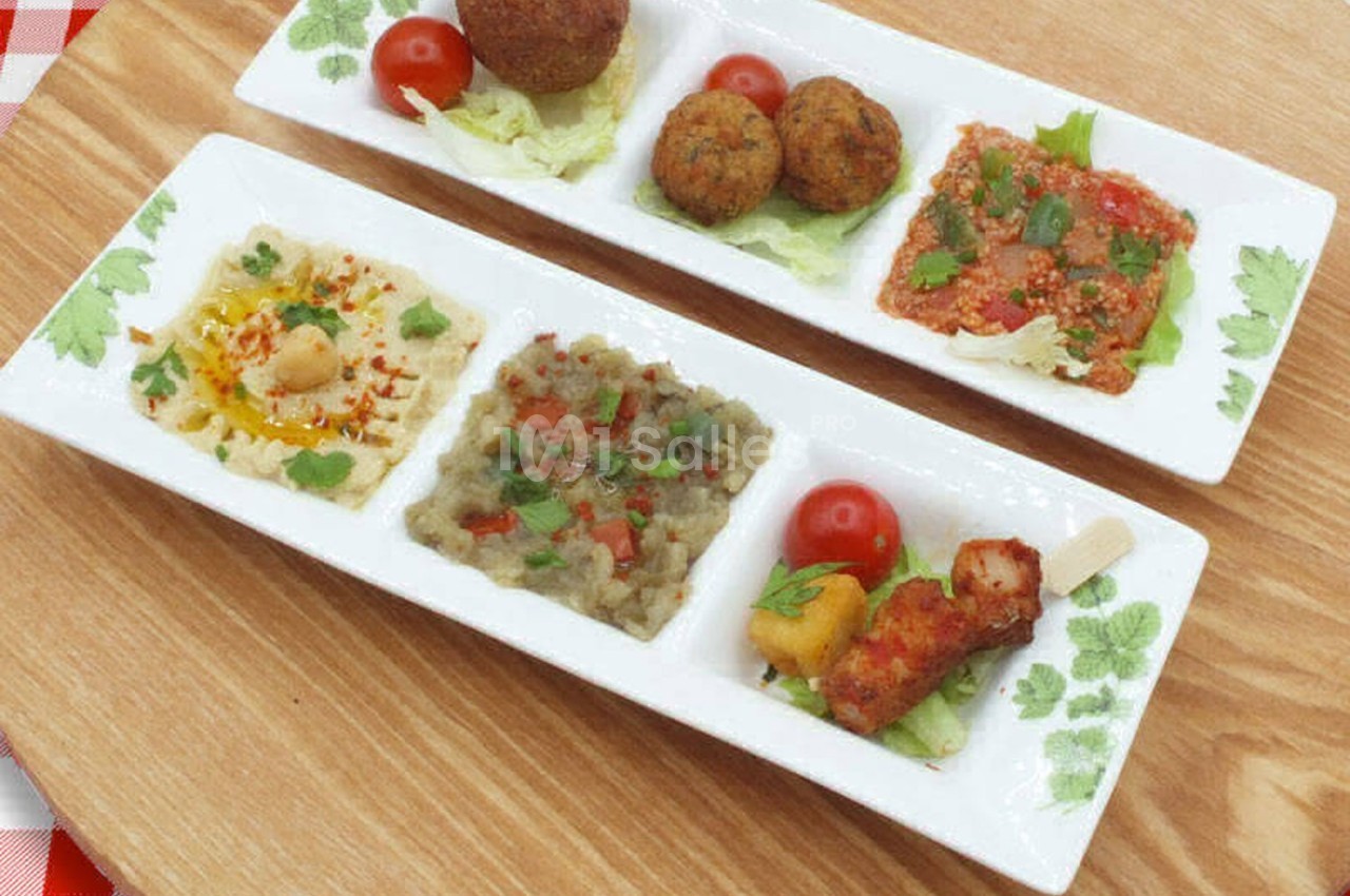 Assiette compartimentée avec mezzés variés : falafels, houmous, caviar d'aubergine, salade et légumes grillés.