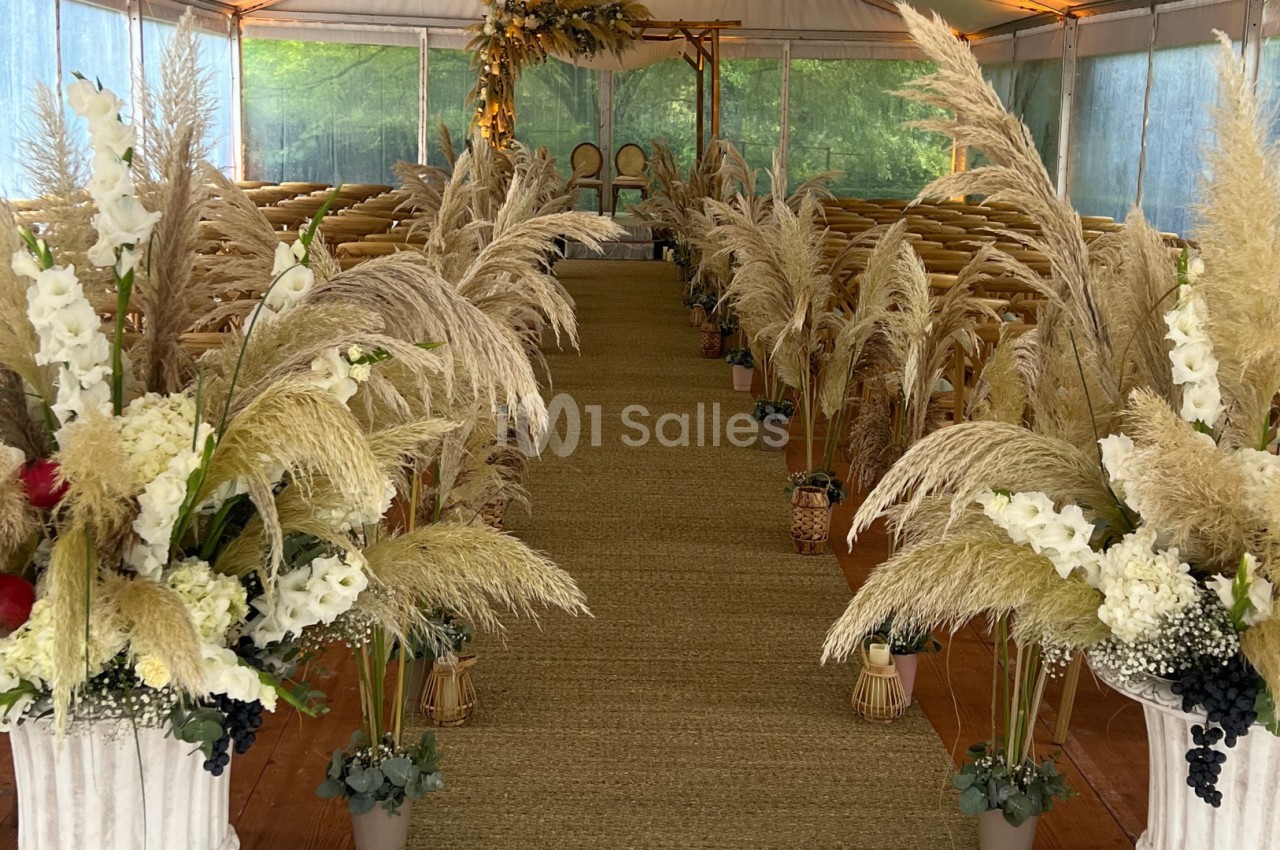 Allée centrale décorée de fleurs séchées et de pampas, menant à un autel dans une salle de cérémonie lumineuse.