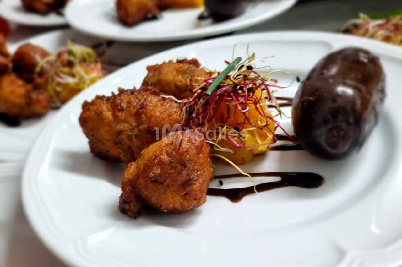 Assiette composée d'accras dorés, boudin noir, purée de légumes et pousses décoratives avec filet de sauce.