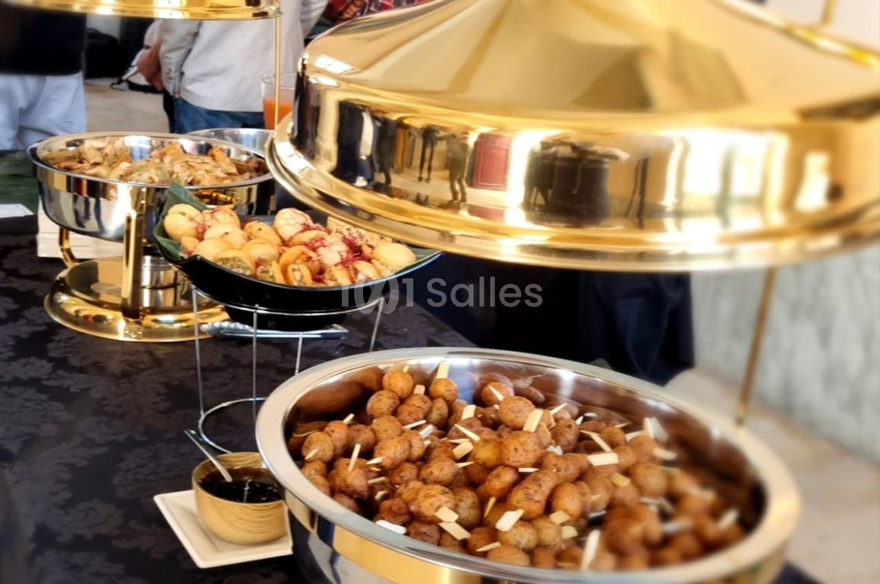 Buffet avec plats de pommes de terre rôties, amuse-bouches variés et sauces, sous des cloches dorées.