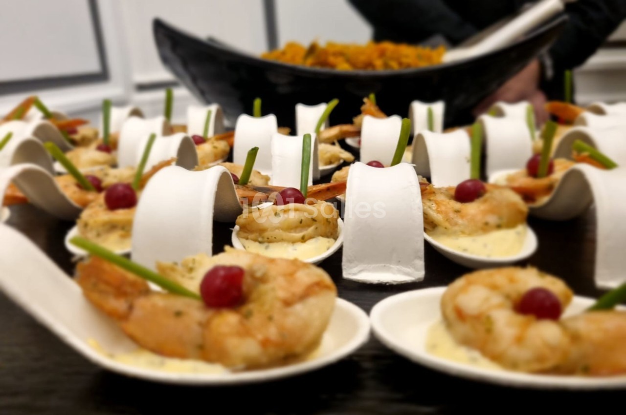 Crevettes servies sur des cuillères individuelles avec sauce, cerises et décoration, présentées sur une table.