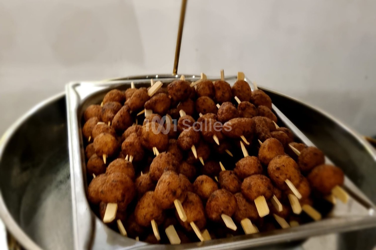 Brochettes de boulettes frites disposées dans un plateau en métal, prêtes à être servies.