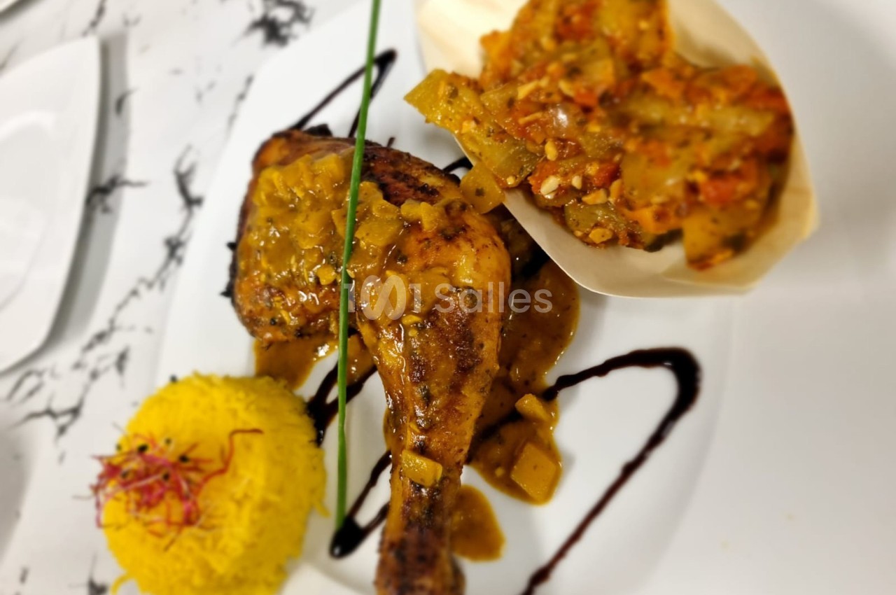 Poulet rôti avec sauce épicée, accompagné de riz safrané et légumes mijotés, présenté sur une assiette blanche.