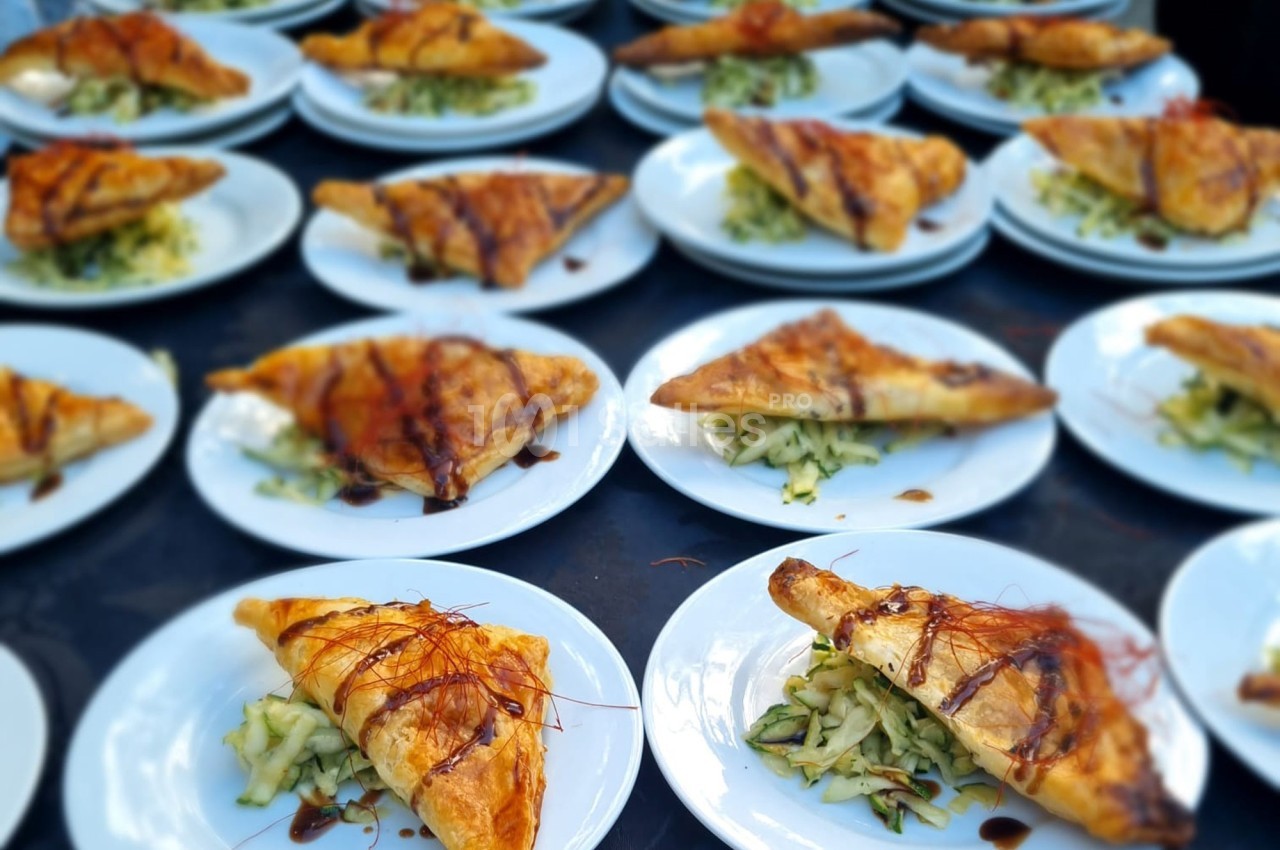 Assiettes garnies de feuilletés dorés accompagnés de légumes râpés et décorés de sauce.