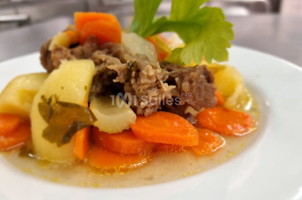 Assiette de ragoût de légumes et viande, avec carottes, pommes de terre et céleri, servie dans un bouillon.
