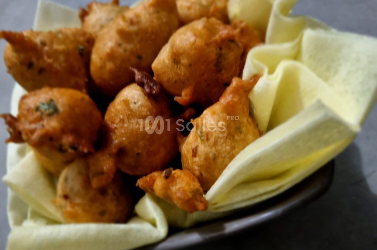 Beignets dorés et croustillants disposés dans un bol garni de serviettes en tissu clair.