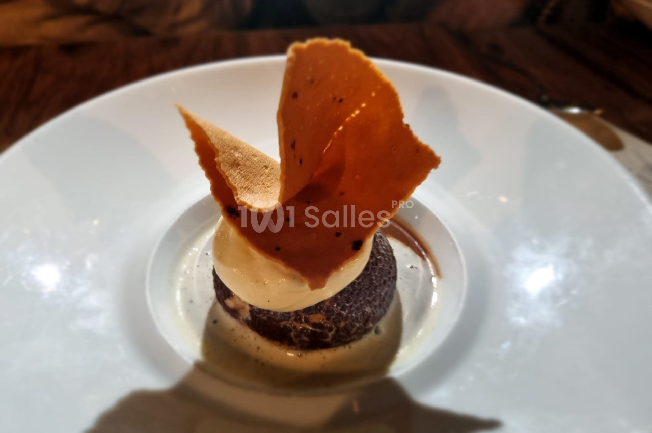 Dessert composé d'une boule de glace sur un fondant au chocolat, décoré d'une fine tuile croustillante.
