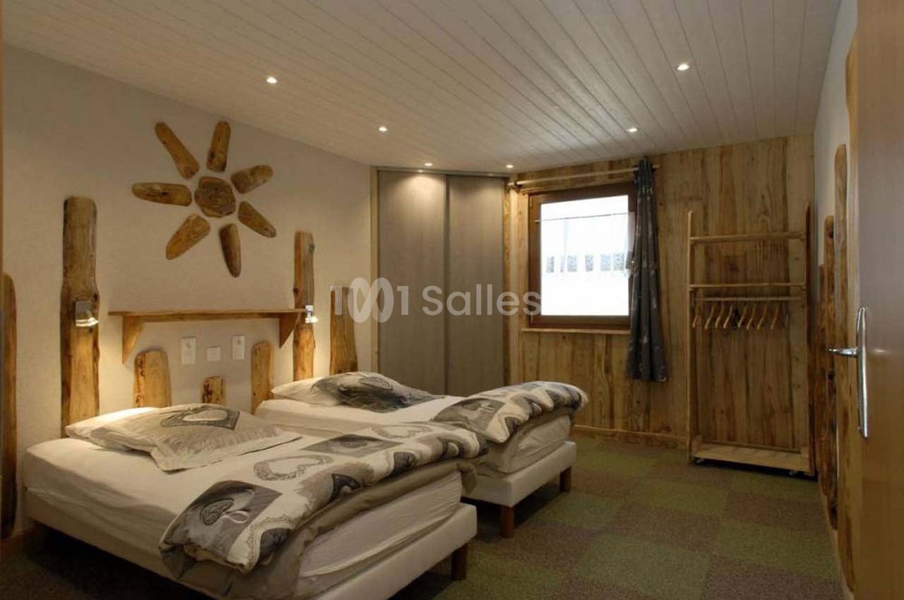 Chambre avec deux lits simples, décor en bois naturel, éclairage doux et fenêtre avec rideau sombre.