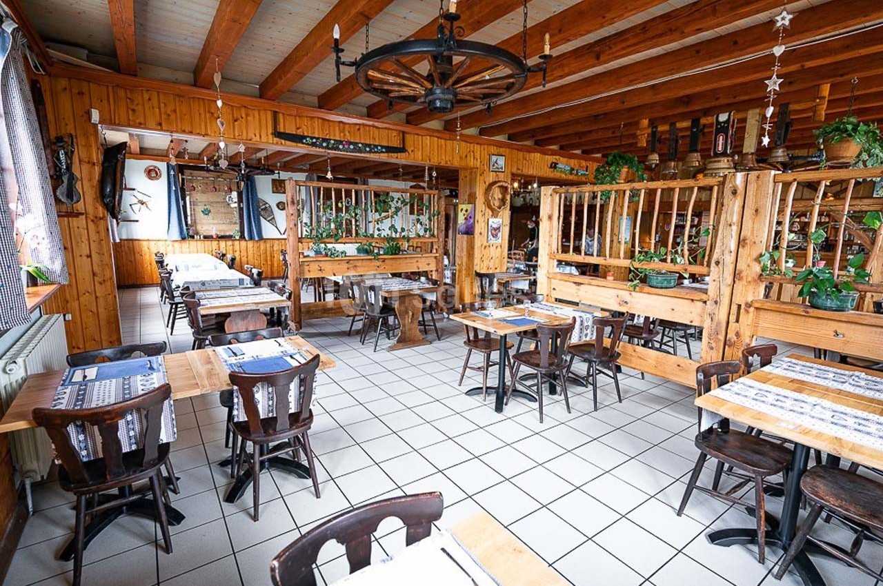 Salle de restaurant rustique avec mobilier en bois, décoration traditionnelle et lumière naturelle.
