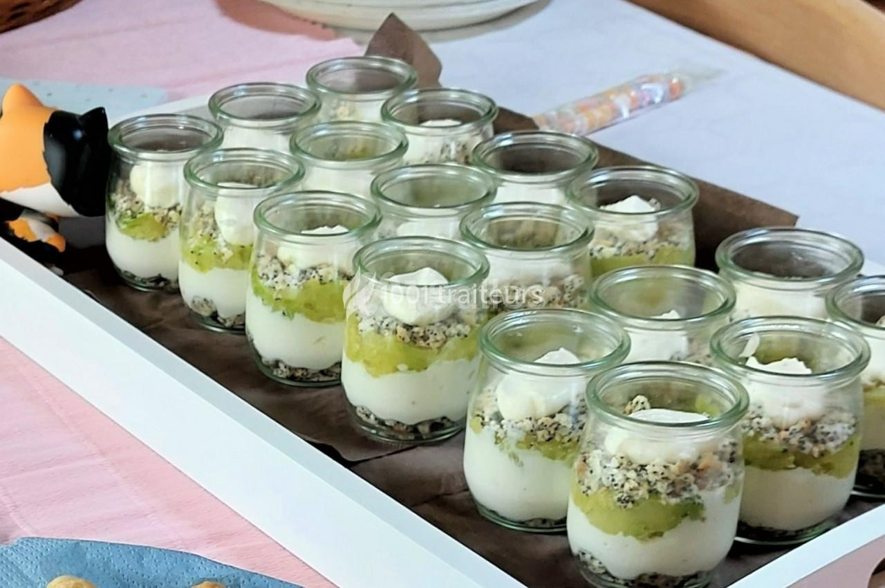 Desserts en verrines composés de couches de crème, de fruits et de crumble, présentés sur un plateau blanc.