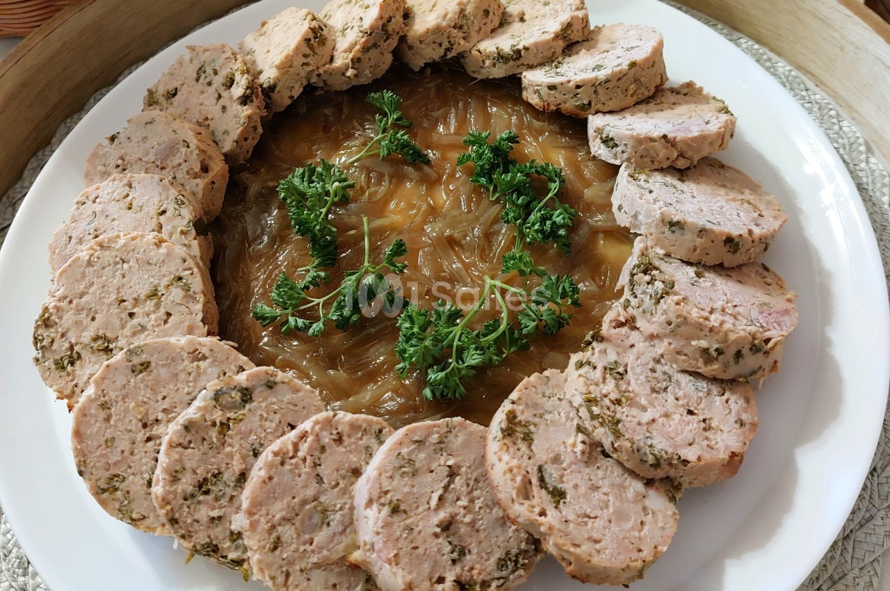 Assiette de rondelles de saucisse aux herbes disposées en cercle autour d'un lit d'oignons caramélisés, décorée de persil.