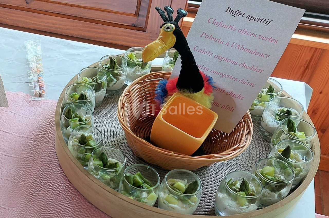 Buffet apéritif avec verrines de légumes verts disposées autour d'une corbeille contenant une décoration colorée.