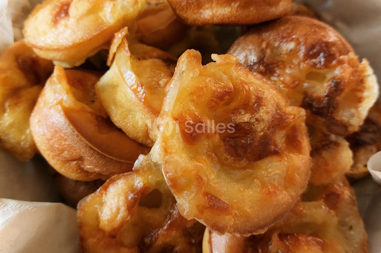 Assortiment de petits gougères dorés et croustillants, disposés dans un panier en tissu clair.