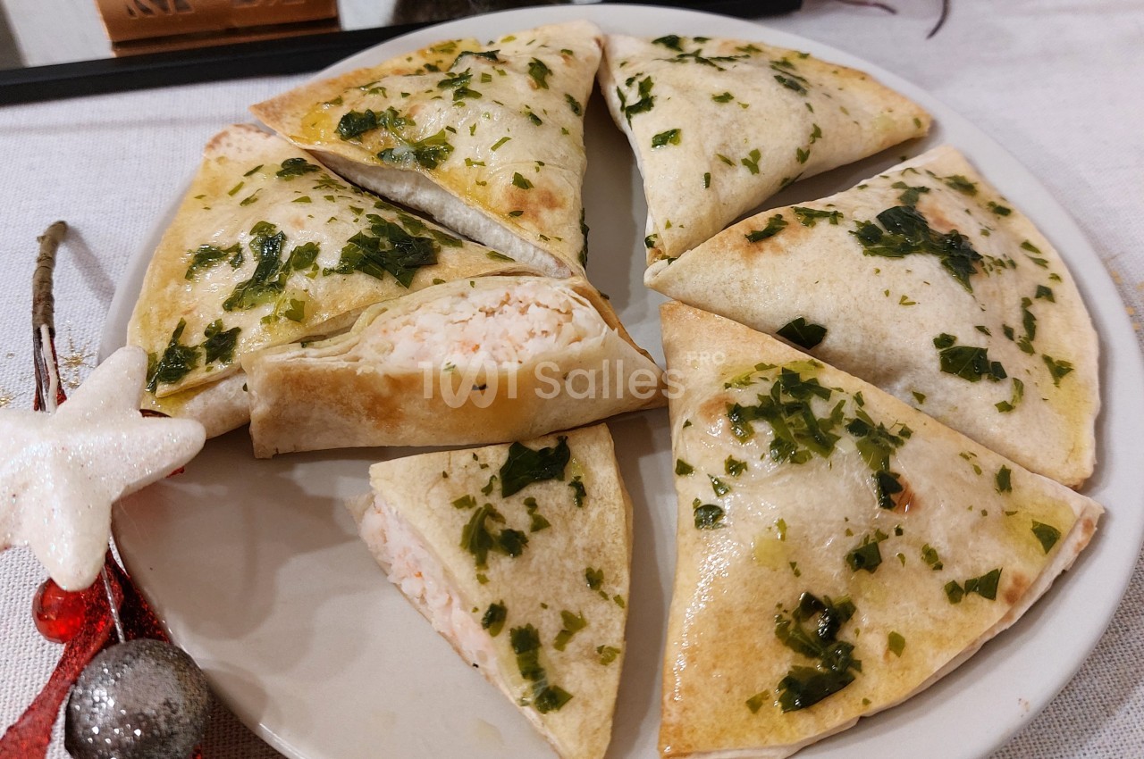 Assiette de triangles de pâte garnis d'une farce crémeuse, décorés de persil et disposés en cercle.