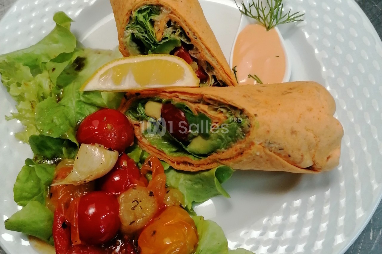 Wrap garni de légumes frais, accompagné de salade verte, tomates cerises rôties et sauce à part.