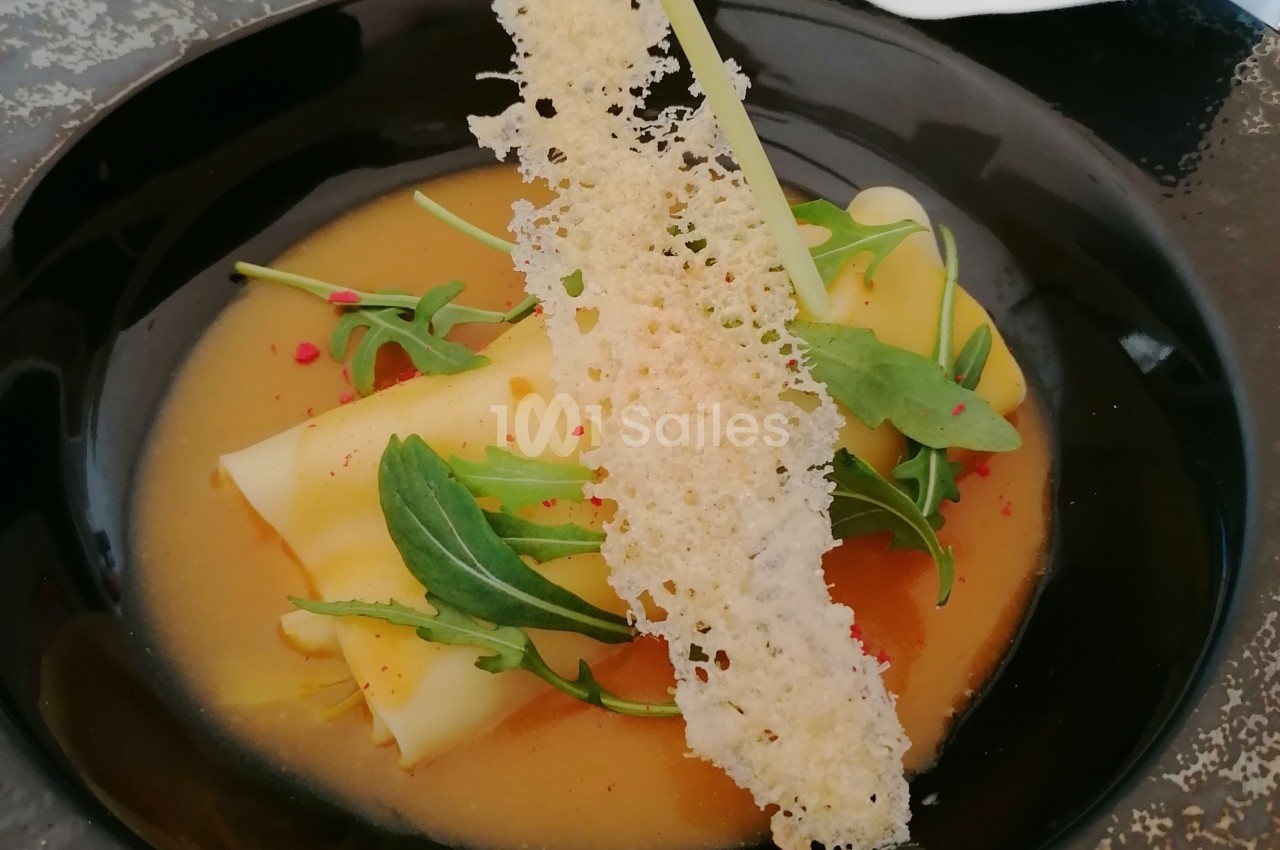 Assiette de ravioles garnies, servies avec une sauce crémeuse, roquette et tuile croustillante.
