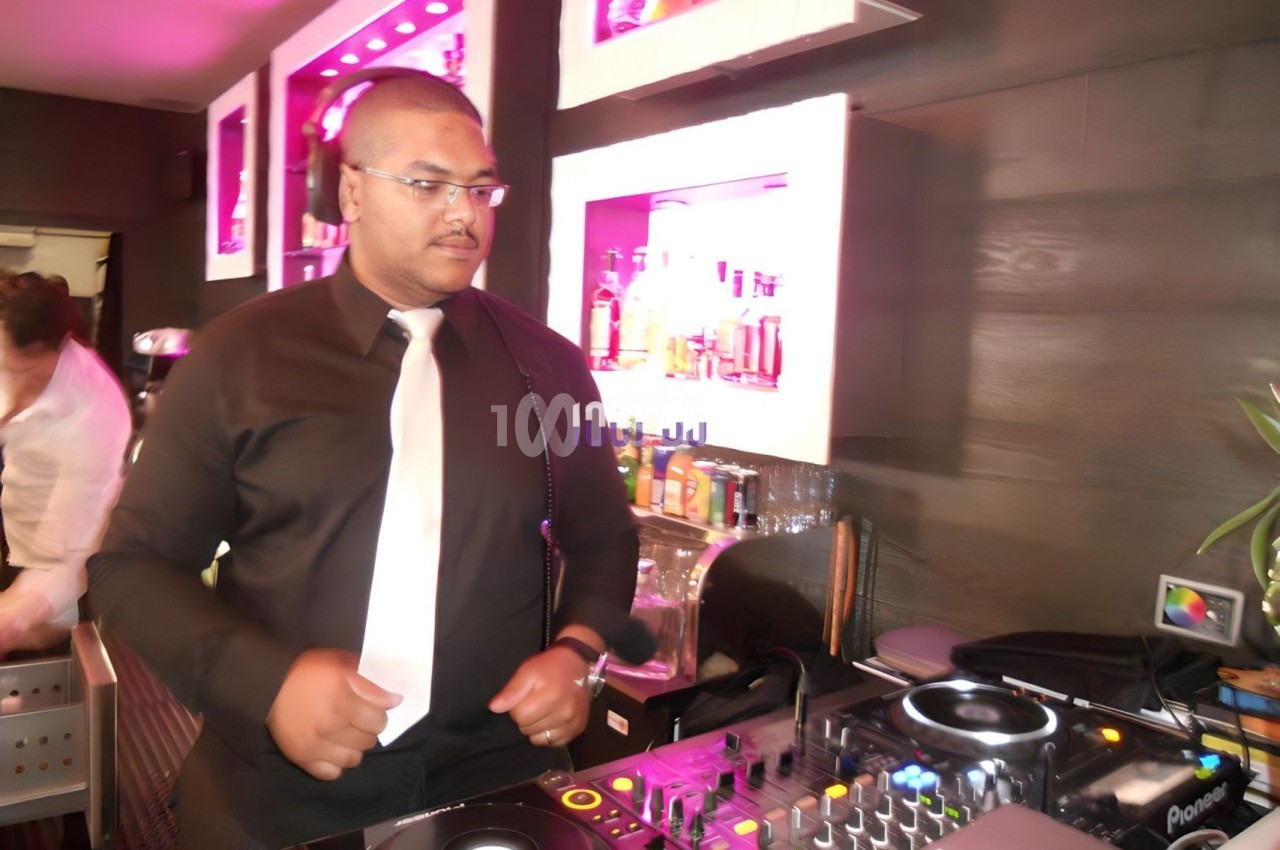 Un DJ mixant de la musique dans un bar avec des lumières roses et un équipement de mixage.