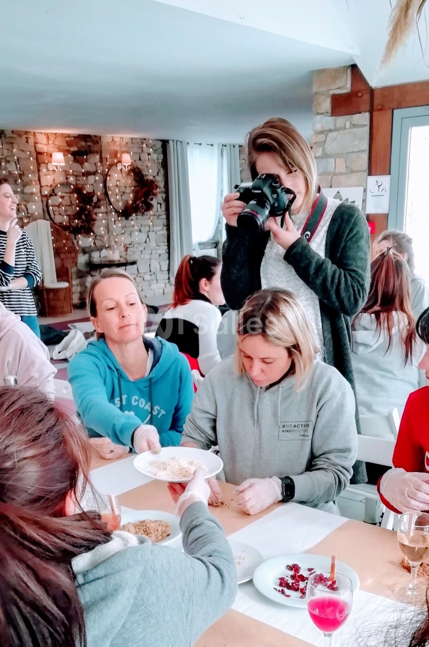 Un groupe de personnes participe à un atelier créatif autour d'une table, une femme prend des photos.