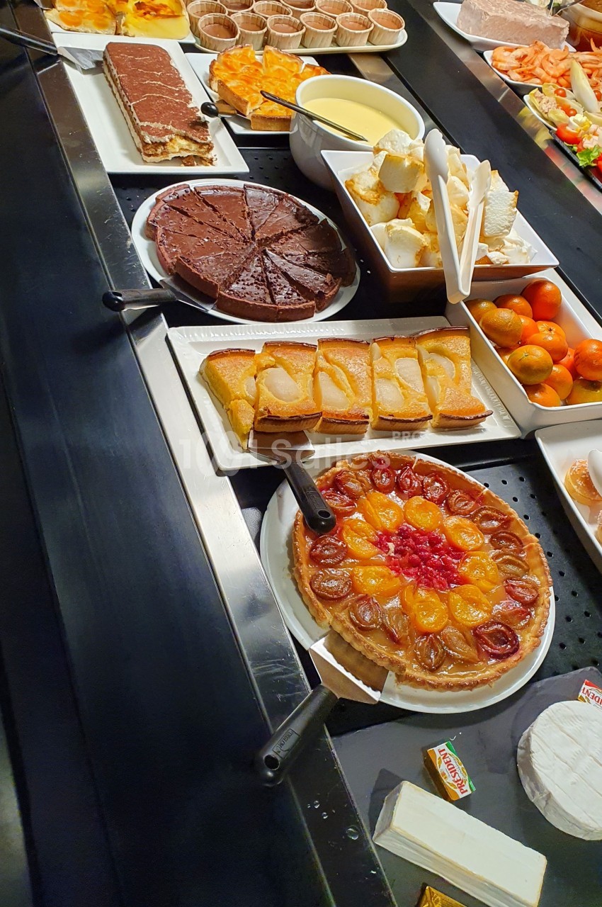 Buffet de desserts variés comprenant tartes, gâteaux, fromages et fruits disposés sur un comptoir.