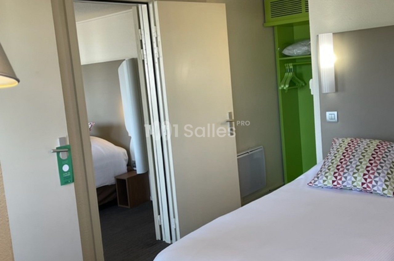 Deux chambres d'hôtel communicantes avec lits faits, penderie ouverte et décoration sobre.