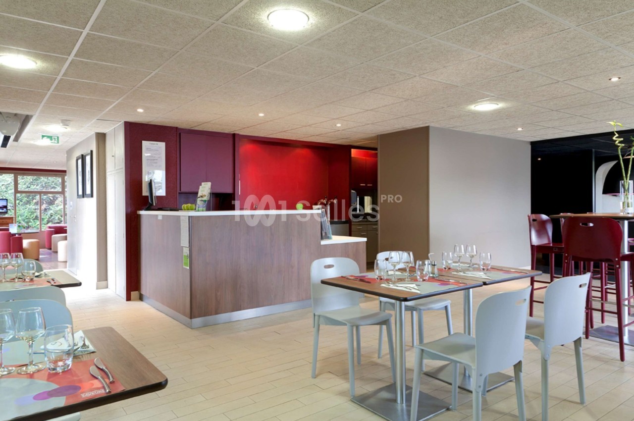 Salle de restaurant lumineuse avec tables dressées, comptoir en bois et chaises modernes dans un décor épuré.