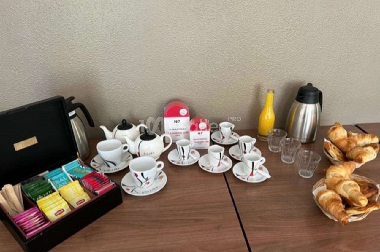 Table avec théières, tasses, assortiment de thés, carafes, verres, jus d'orange et viennoiseries.