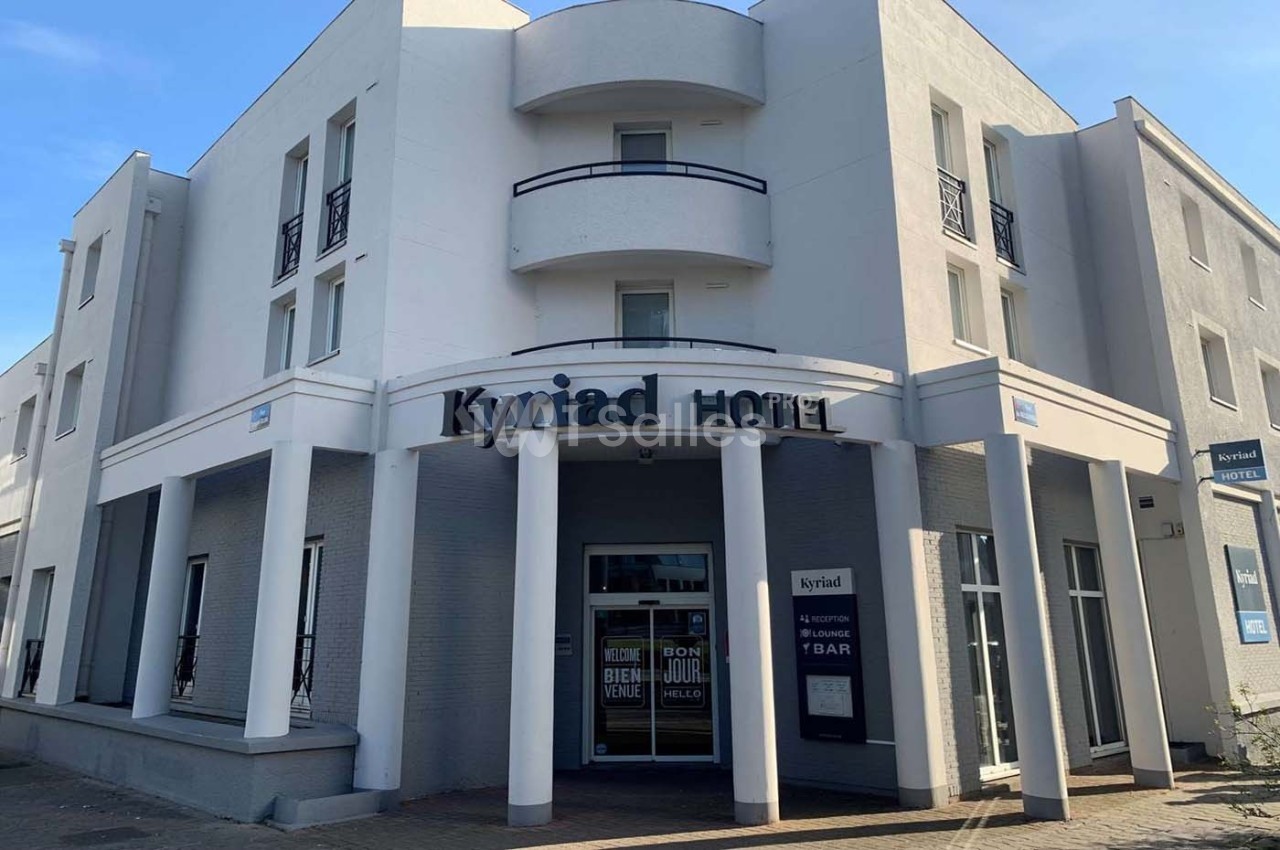 Façade d'un hôtel moderne avec balcons, entrée principale vitrée et enseigne ’Kyriad Hotel’.
