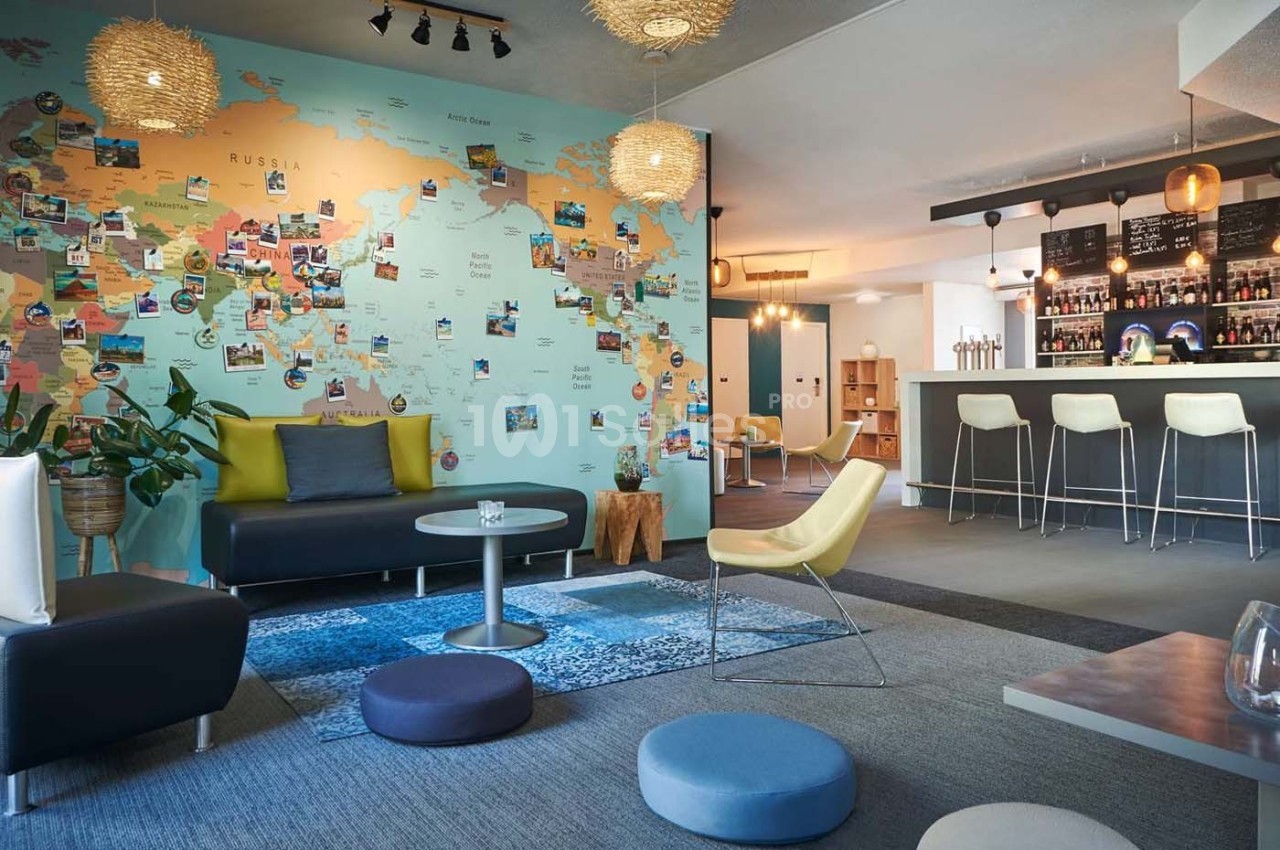 Espace lounge moderne avec fauteuils, tables basses et une carte du monde décorative sur le mur.