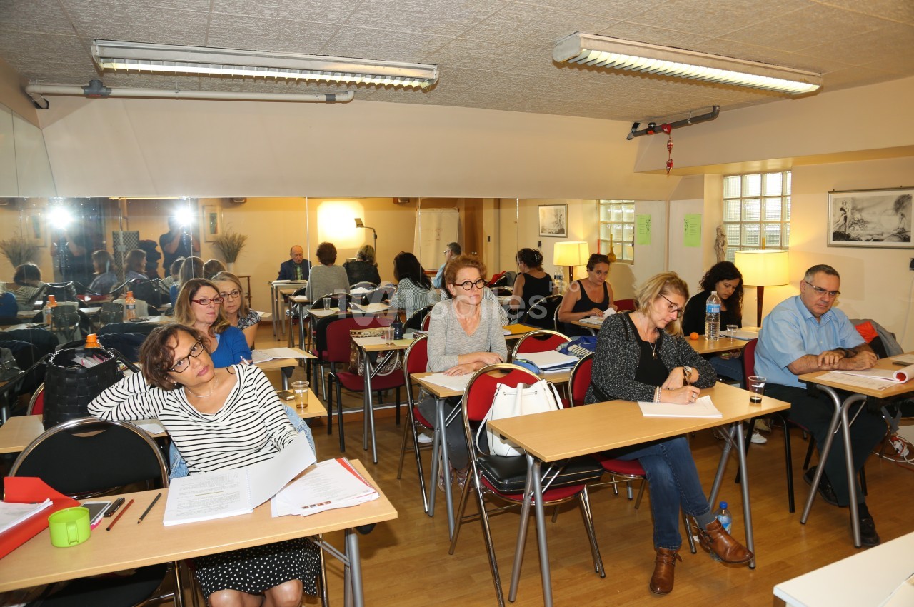 Des adultes assis dans une salle de classe, attentifs ou prenant des notes lors d'une formation ou d'un cours.