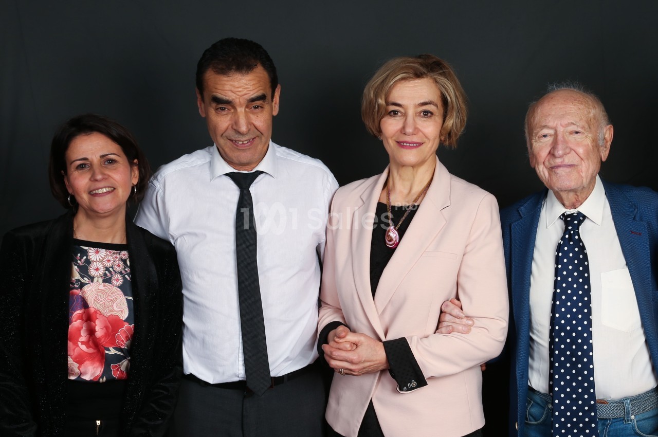 Quatre personnes posant ensemble devant un fond sombre, souriantes et habillées de manière formelle.