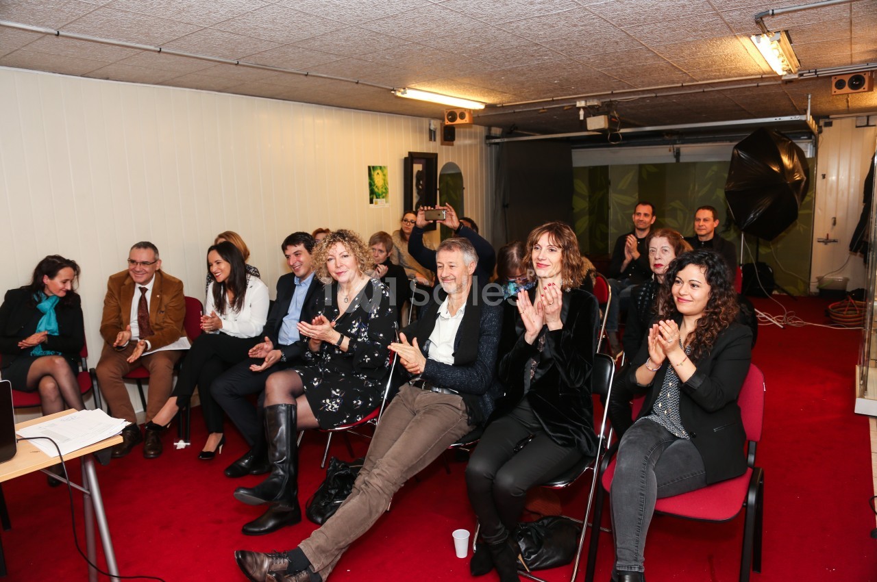 Un groupe de personnes assises dans une salle, applaudissant et regardant vers l'avant.