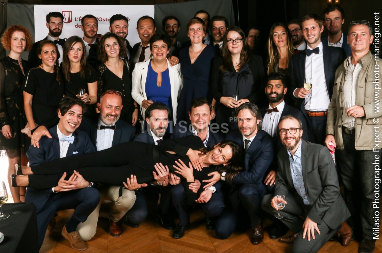 Un groupe de personnes posant ensemble lors d'un événement, certaines souriantes et habillées de manière élégante.