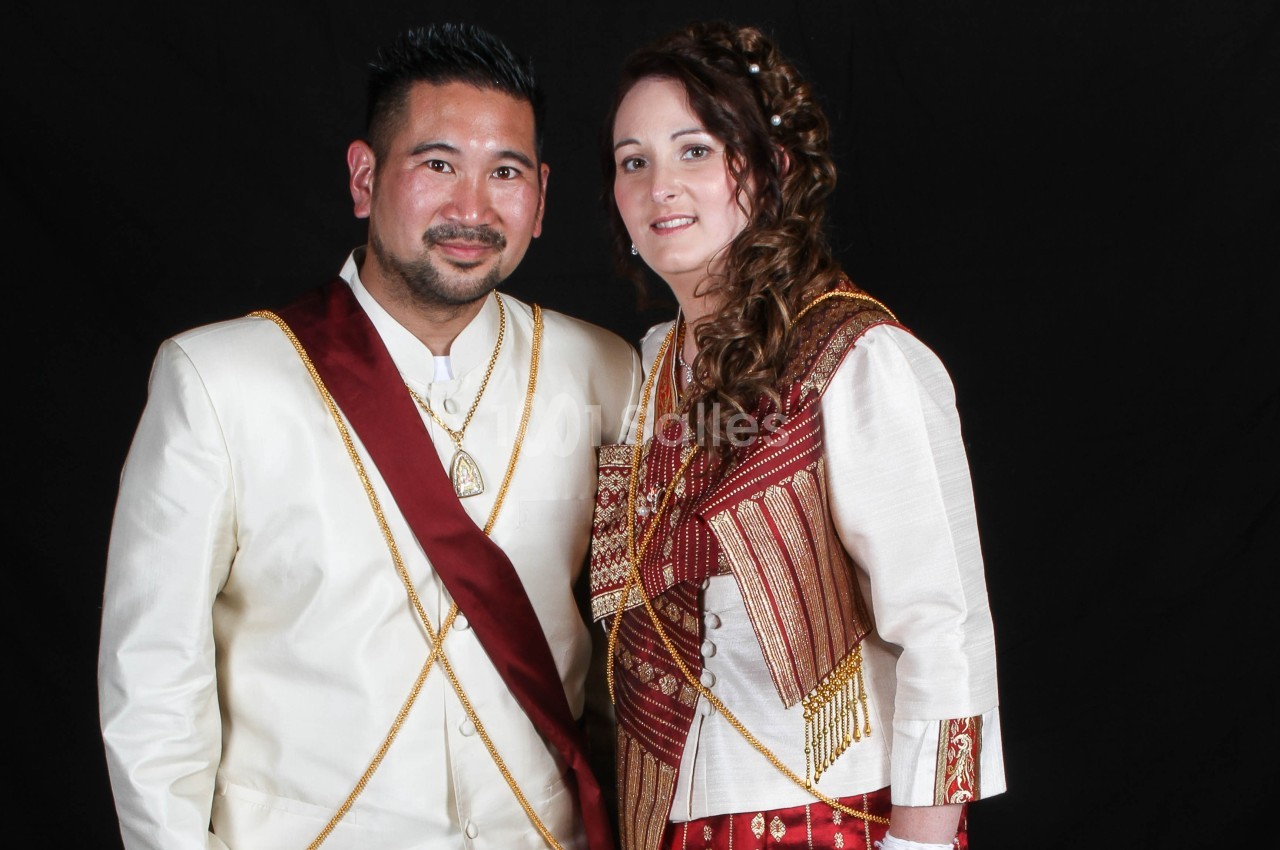 Un homme et une femme en tenues traditionnelles posent devant un fond noir.