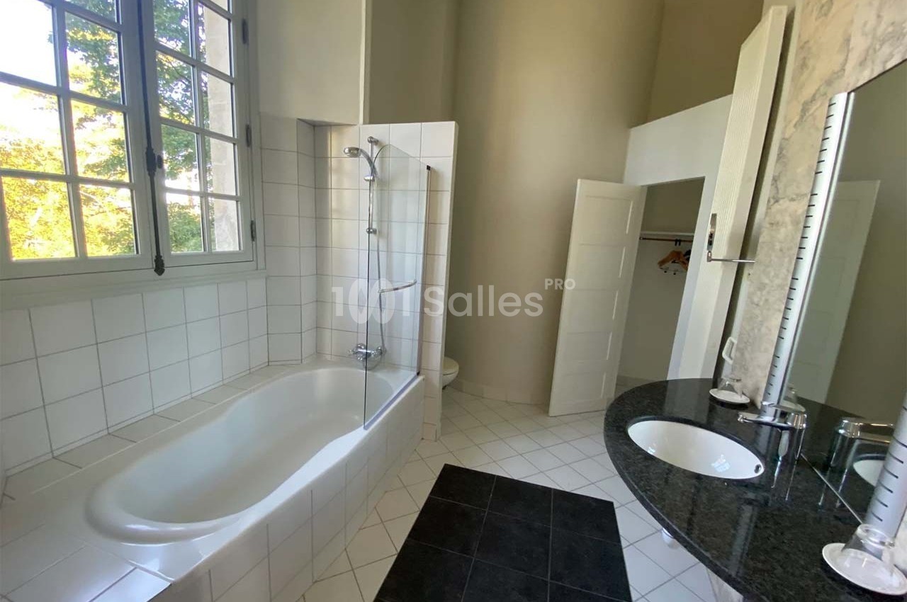 Salle de bain lumineuse avec baignoire, douche intégrée, lavabo sur plan en marbre et fenêtre donnant sur l'extérieur.