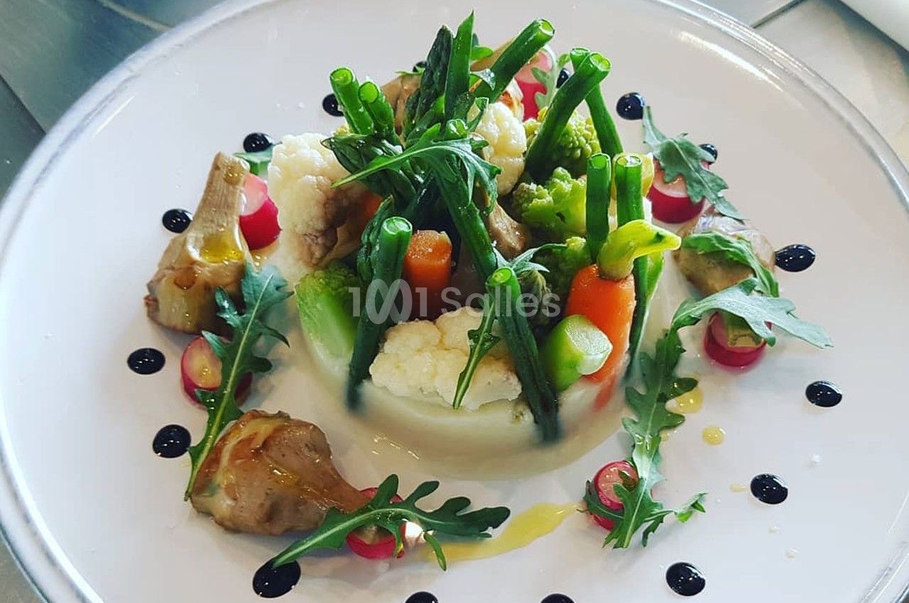 Assiette de légumes variés joliment dressés avec des touches de sauce et des décorations de roquette.